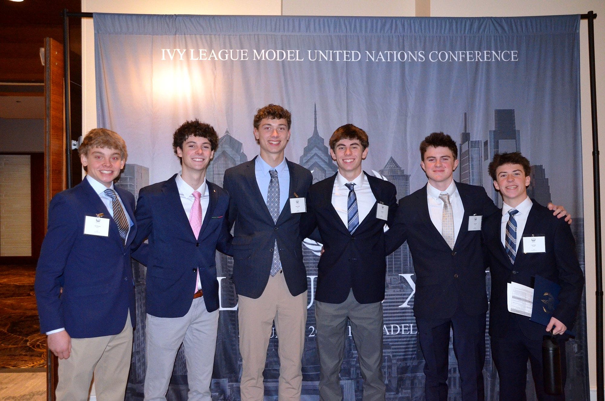 Six delegates posing in front of the Ivy League Model United Nations Conference banner